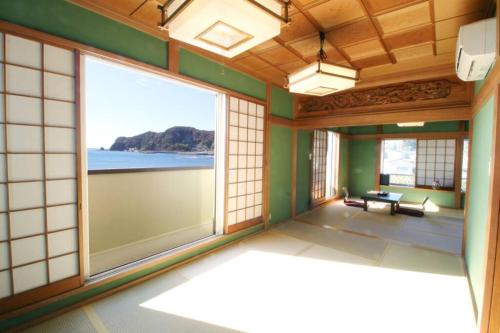 a room with a large window with a view of the ocean at Uhome Kamogawa Villa in Kamogawa
