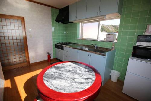a kitchen with a red stool in the middle of a kitchen at Uhome Kamogawa Villa in Kamogawa