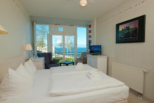 Panorama Hotel Lohme في لوهم: غرفة نوم بسرير ابيض وغرفة معيشة
