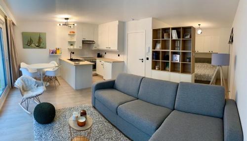 ein Wohnzimmer mit einem blauen Sofa und einer Küche in der Unterkunft SeaYouSoon Nieuwpoort-Bad in Nieuwpoort