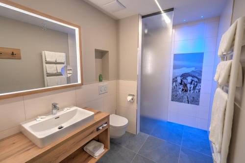 een badkamer met een wastafel, een toilet en een douche bij Der Siegeler B&B - this lifestylehotel rocks in Mayrhofen