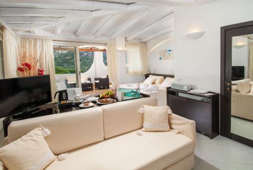 a living room with a couch and a television at Hotel Punta Est in Baja Sardinia