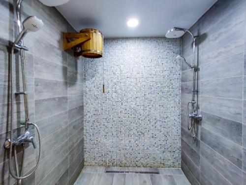 a bathroom with a shower with a tiled wall at Hotel Avrora in Vityazevo