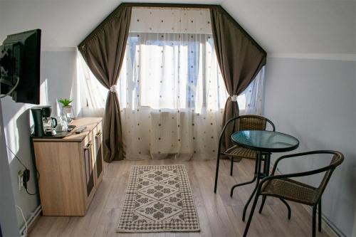 Zimmer mit einem Tisch, Stühlen und einem Fenster in der Unterkunft Casa Mocanitei in Vişeu de Sus