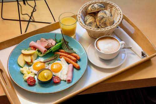 a tray with a plate of breakfast food and a cup of coffee at Hotel Kortowo in Poznań