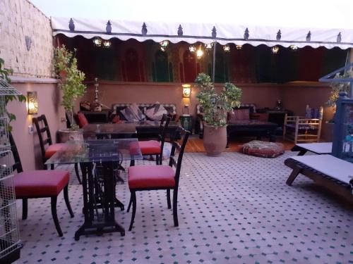 uma sala de jantar com uma mesa de vidro e cadeiras em Riad Simon em Marrakech