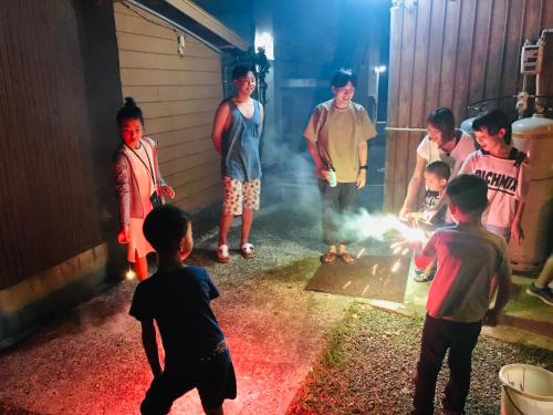 un grupo de niños parados alrededor de un fuego en un garaje en Guest house & Bar Diamond Head, en Mihana