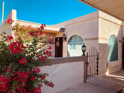ein Haus mit roten Blumen und einem Zaun in der Unterkunft Central French Charm in Tucson in Tucson