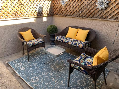 a patio with two chairs and a table with yellow pillows at Central French Charm in Tucson in Tucson