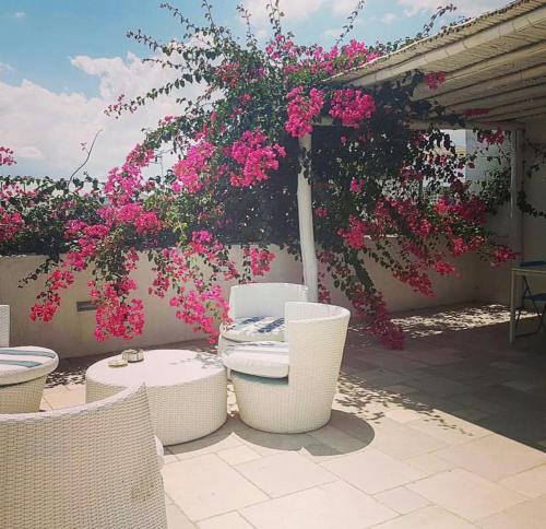 a patio with pink flowers and tables and chairs at Antico Mondo Rooms & Suites in Polignano a Mare