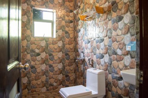 a bathroom with a toilet and a window at Green Nest Hostel, Baga - Arpora in Arpora