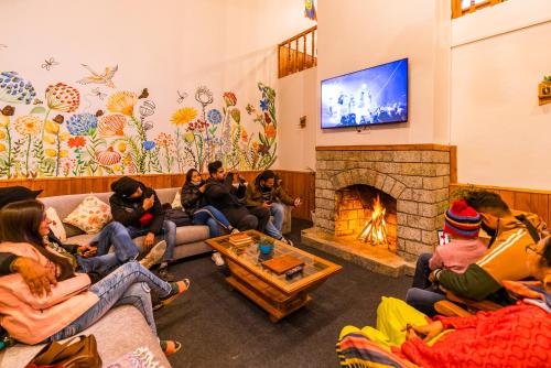 a group of people sitting in a living room with a fireplace at Keekoo Manali - Private Rooms & Dorms in Manāli