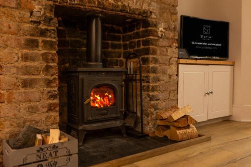 a wood stove in a brick wall with logs at Stylish Coastal Retreat with Hot Tub & Log Burner in Margate in Margate