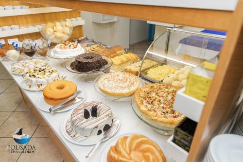 a table with many different types of cakes and pastries at Pousada Ilha dos Lobos in Torres