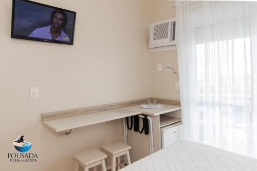 a room with a kitchen with a tv on the wall at Pousada Ilha dos Lobos in Torres