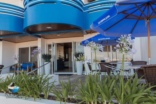 un edificio blu con tavoli, sedie e ombrelloni di Pousada Ilha dos Lobos a Torres