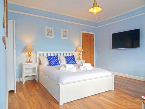 a bedroom with a white bed with blue walls at Nautical Apartment by Seaside Llandudno in Llandudno