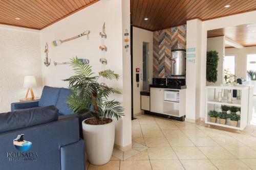 a living room with a blue couch and a plant at Pousada Ilha dos Lobos in Torres