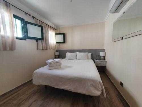 1 dormitorio con 1 cama blanca grande y 2 ventanas en APARTAMENTO SUNSET PUERTO DE MOGAN, en Puerto de Mogán