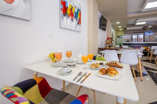 una mesa blanca con desayuno y bebidas. en Hotel Calimera, en Santa Teresita