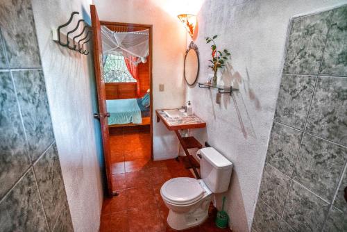 a bathroom with a toilet and a sink and a mirror at Casitas Las Flores in Puerto Viejo