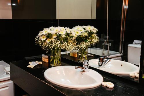 Santo Thyrso Hotel في سانتو تيرسو: حمام مع حوض وزهور في مرآة
