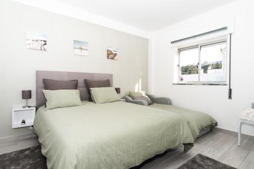 una camera da letto bianca con un letto grande e una finestra di TOMÁS HOME a Nazaré