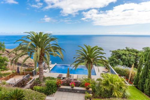 a view of a swimming pool with palm trees and the ocean at Casa Martinhos by LovelyStay in Caniço