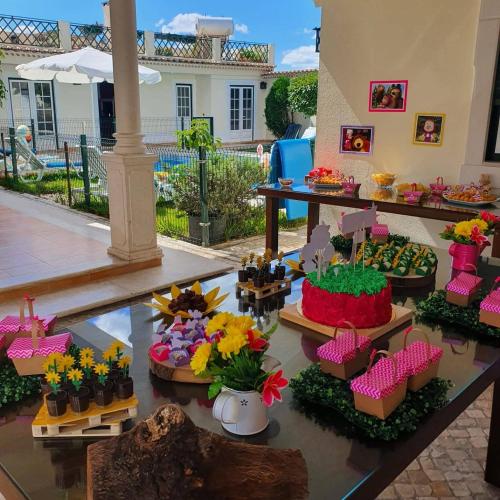 a table with many different types of cakes and flowers at Férias Inesquecíveis in Carregado