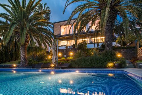 a swimming pool in front of a building with palm trees at Casa Martinhos by LovelyStay in Caniço