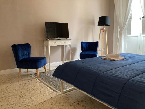 una camera da letto con due sedie blu e un letto e una televisione di Casa- Corso Umberto a Taranto