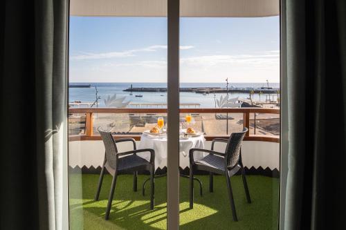
a dining room table with chairs and a window at Apartamentos Islamar Arrecife in Arrecife
