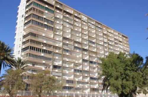 a large white building with trees in front of it at 1a línea con PISCINA Nuevo in Cullera