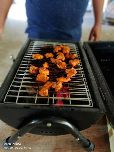 een persoon kookt eten op een grill bij Le CharMin in Kodaikānāl