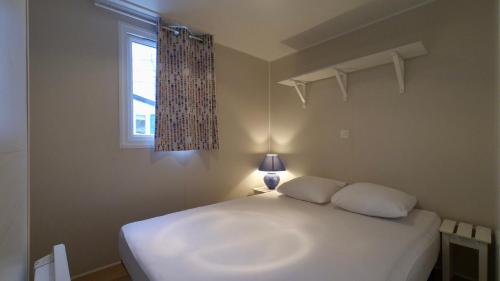 a white bed in a bedroom with a window at Camping Municipal La Prade in Sorgeat