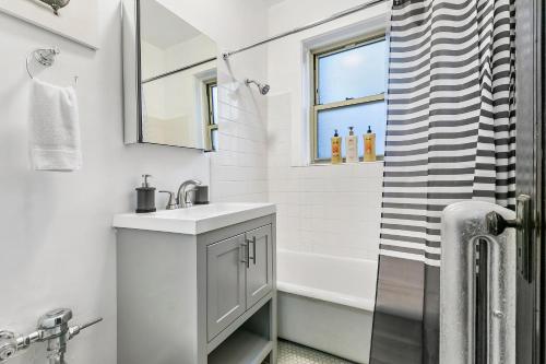 a white bathroom with a sink and a shower at Vibrant 1BR Apartment in Roscoe Village - Marshfield N3 in Chicago