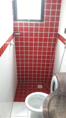 a red tiled bathroom with a toilet and a window at The House Pousada e Hospedagem Enseada- Guarujá in Guarujá