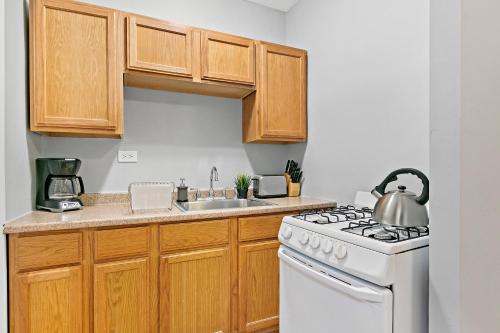 a kitchen with wooden cabinets and a white stove top oven at 1-bedroom Cozy & Modish Apt - Marshfield W2 rep in Chicago