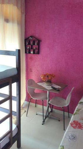 uma mesa e cadeiras num quarto com uma parede rosa em The House Pousada e Hospedagem Enseada- Guarujá no Guarujá