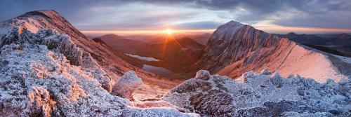 a view of a snowy mountain with the sun setting at Coastal Gem Apartment by Seaside Llandudno in Llandudno