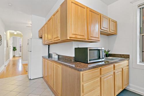 a kitchen with wooden cabinets and a microwave at Comfy 2BR Apartment near Wrigley Field - Grace 3 in Chicago