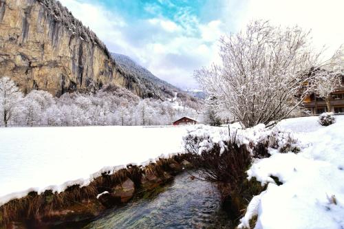 a snow covered field with a river and a mountain at Apartment Breithorn - Charming home - free parking & Wifi in Lauterbrunnen