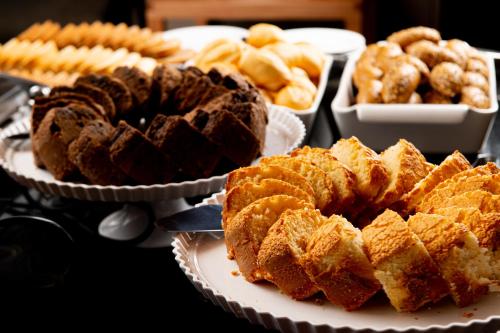 a table topped with plates of pastries and other foods at Intercity Portofino Florianópolis in Florianópolis