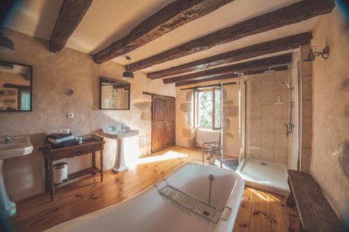 une grande salle de bain avec une baignoire et un lavabo dans l'établissement Le Noyer, à Rougnat