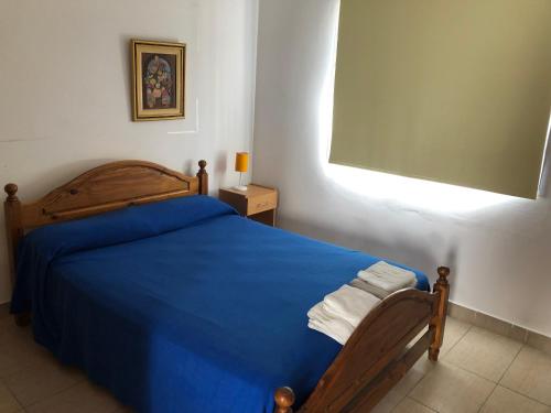 a bedroom with a bed with a blue blanket at Apart Orange in Pilar