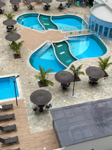 an overhead view of two swimming pools with tables and chairs at Aquarius Residence Caldas Novas 701D in Caldas Novas