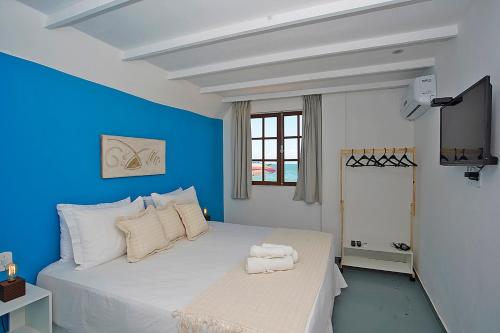 a bedroom with a white bed with a blue wall at Sofia's on the Beach in Búzios