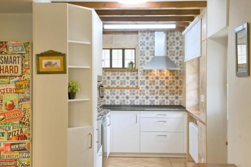 a kitchen with white cabinets and blue and white tiles at Casas Rurales El Llugarón in Miravalles