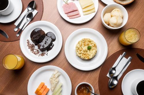 a table with white plates of food on it at Intercity Portofino Florianópolis in Florianópolis