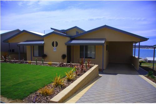 a yellow house with a walkway in front of it at Birubi Holiday Homes Kangaroo Island in Emu Bay